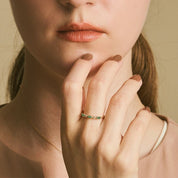 Close-up of a woman wearing a ring with a visible brand logo.