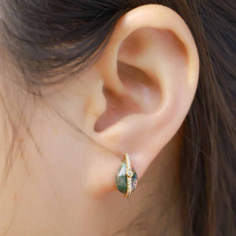 Close-up of an ear wearing a gold and green earring