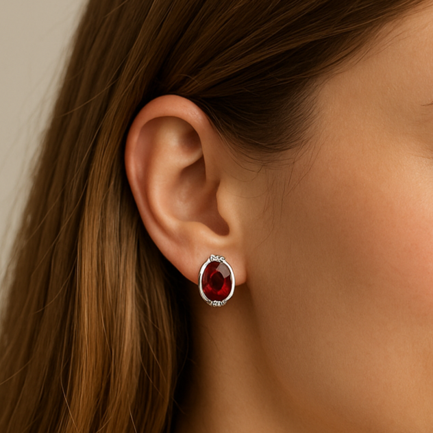 Close-up of an ear wearing a red gemstone earring with a neutral background