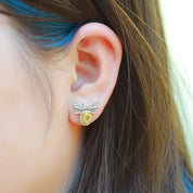 Close-up of an ear wearing a yellow gemstone earring with a silver setting.