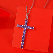 Cross-shaped necklace with purple stones on a red card