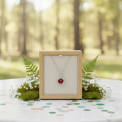 Diamond necklace with red gemstone in a wooden box on a table outdoors