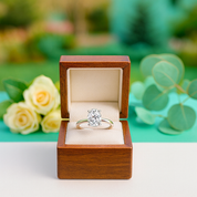 Diamond ring in a wooden box with flowers and greenery in the background