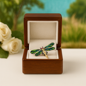Dragonfly-shaped brooch in a wooden box with a scenic background