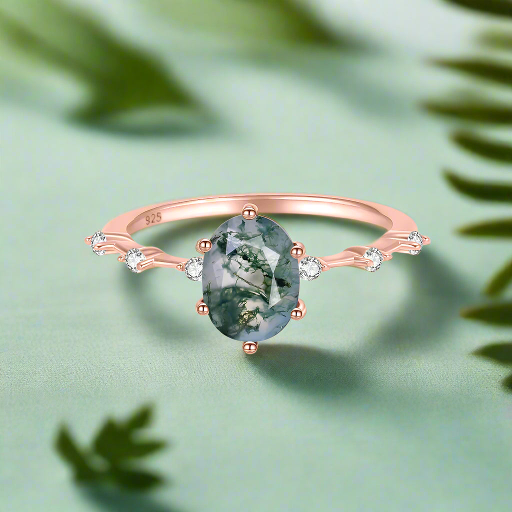 Rose gold ring with a green gemstone and small diamonds on a white background
