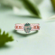 Stack of rose gold rings with a green gemstone on a dark surface