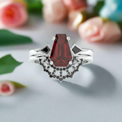 Elegant ring with a red gemstone and black accents on a white background