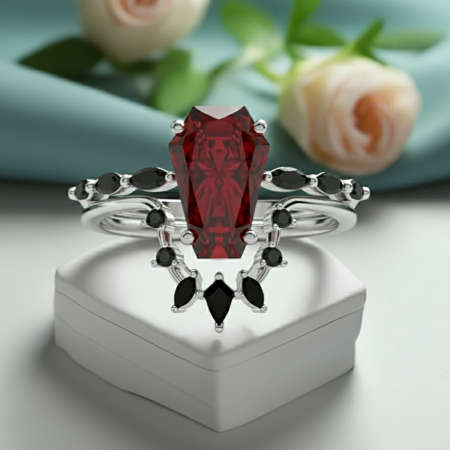 Elegant ring with a red gemstone and black stones on a white box with flowers in the background