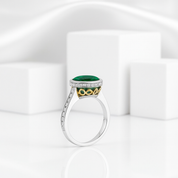 Elegant ring with green gemstone and gold accents on a white background