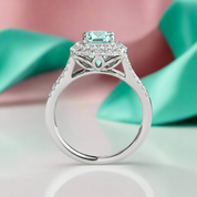 Elegant silver ring with a central gemstone on a soft pink and green background