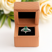 Emerald ring in a wooden box with roses in the background