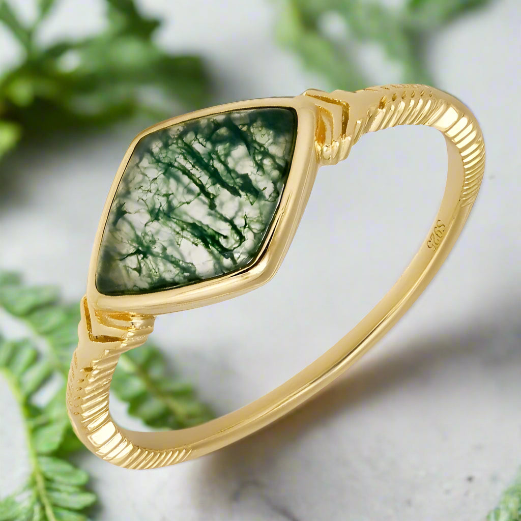 Gold bracelet with a green stone on a white background