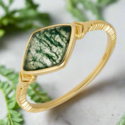 Gold bracelet with a green stone on a white background