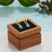 Gold earrings on a wooden stand with a blurred natural background