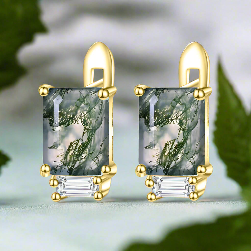 Gold earrings with green gemstones on a white background