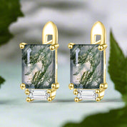 Gold earrings with green gemstones on a white background