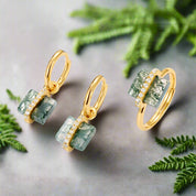 Gold earrings with green stone drops on a white background