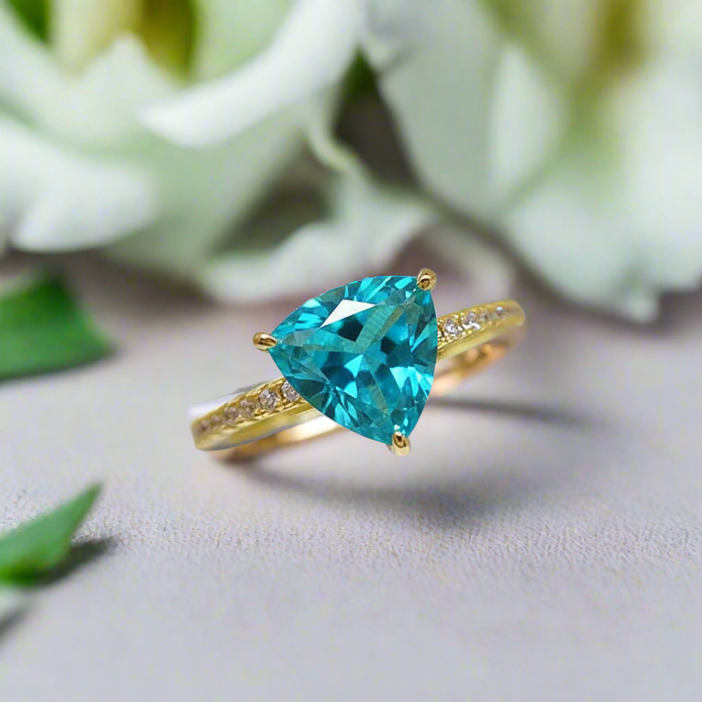 Gold ring with a blue gemstone on a light background