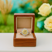 Gold ring with a diamond in a wooden box against a blurred floral background