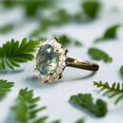 Gold ring with a green gemstone and diamond accents on a dark surface