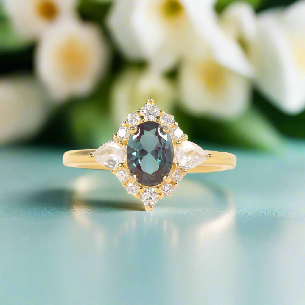 Gold ring with a green gemstone and diamond accents on a soft white background