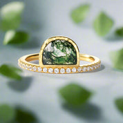 Gold ring with a green gemstone and diamond accents on a white background