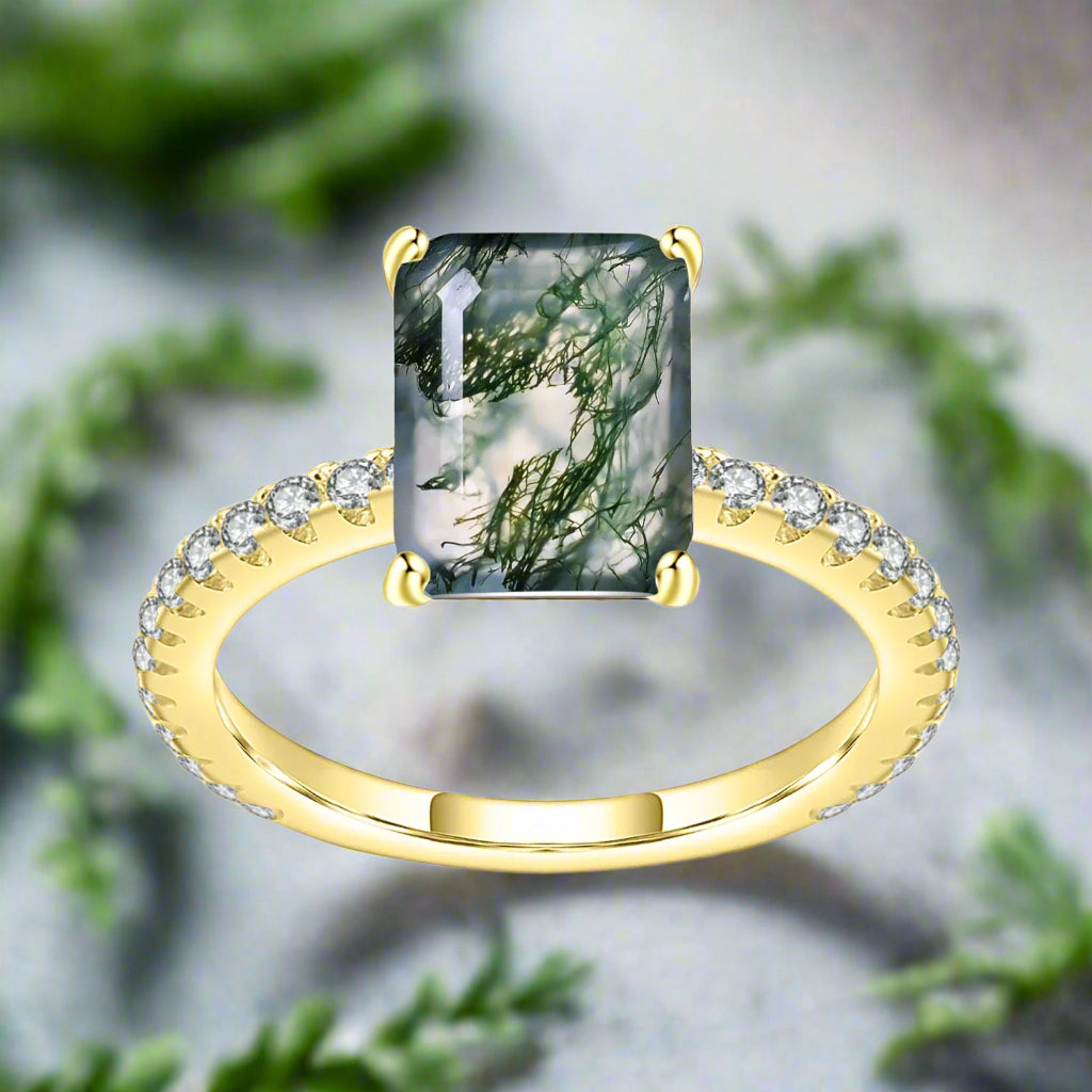 Gold ring with a green gemstone and diamond accents on a white background