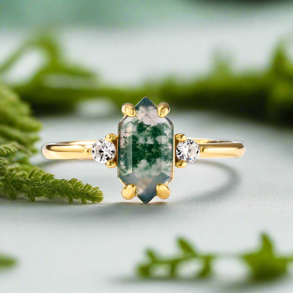 Gold ring with a green gemstone and small diamonds on a light blue background