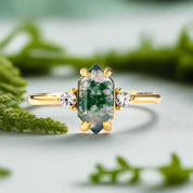 Gold ring with a green gemstone and small diamonds on a light blue background