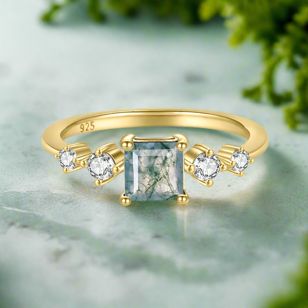 Gold ring with a green gemstone and smaller diamonds on a white background
