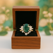 Gold ring with a green gemstone in a wooden box against a blurred natural background