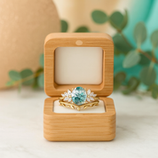Gold ring with a green gemstone in a wooden box on a light background