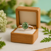 Gold ring with a green gemstone in a wooden box on a natural background