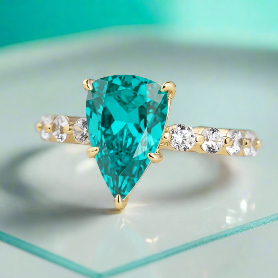 Gold ring with a green gemstone in a wooden box surrounded by roses.