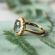 Gold ring with a green gemstone on a dark surface