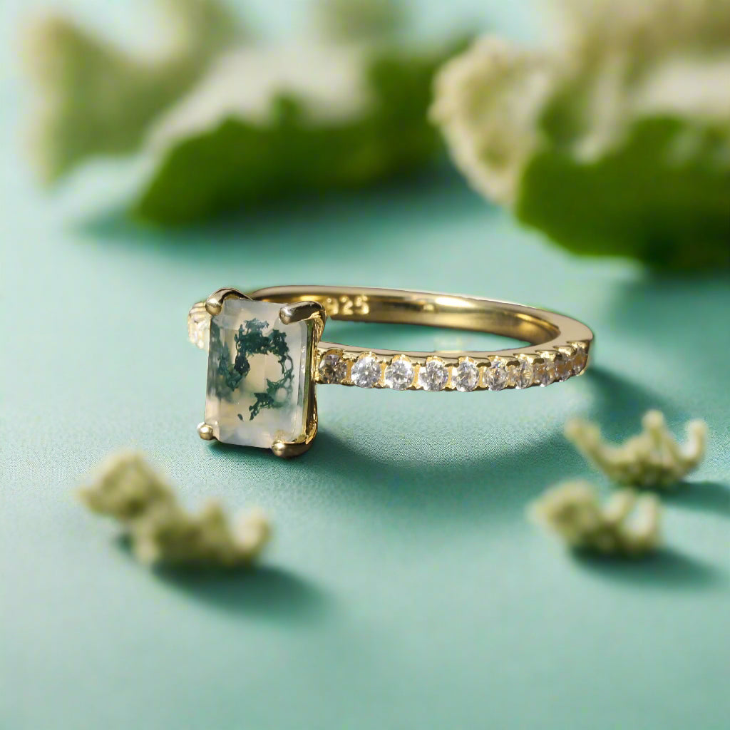 Gold ring with a green gemstone on a dark surface