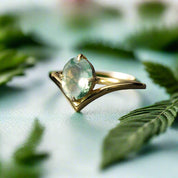 Gold ring with a green gemstone on a dark surface