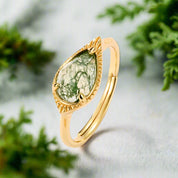 Gold ring with a green gemstone on a white background