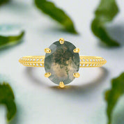 Gold ring with a green gemstone on a white background