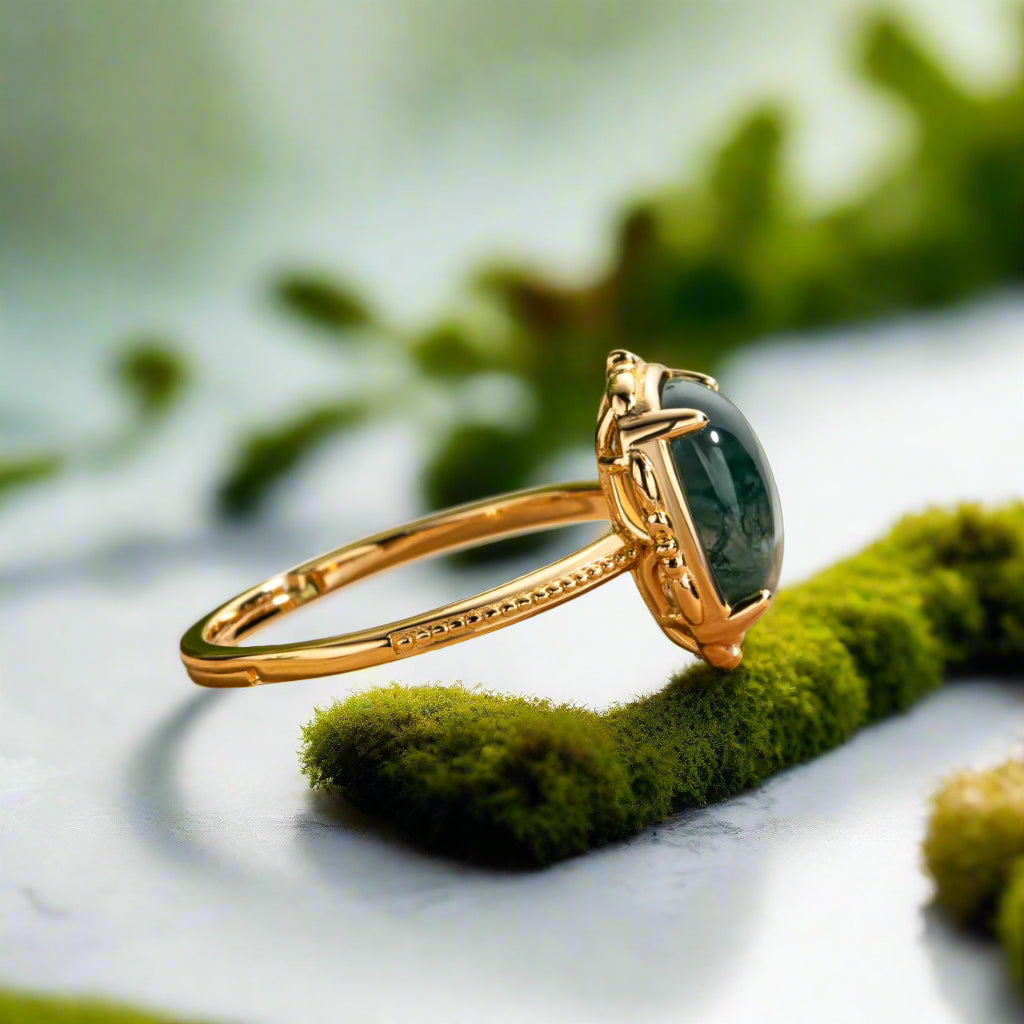 Gold ring with a green gemstone on a wooden surface with a blurred green plant background
