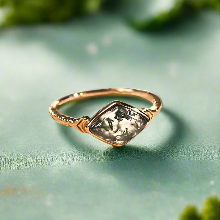 Gold ring with a green gemstone on an open book