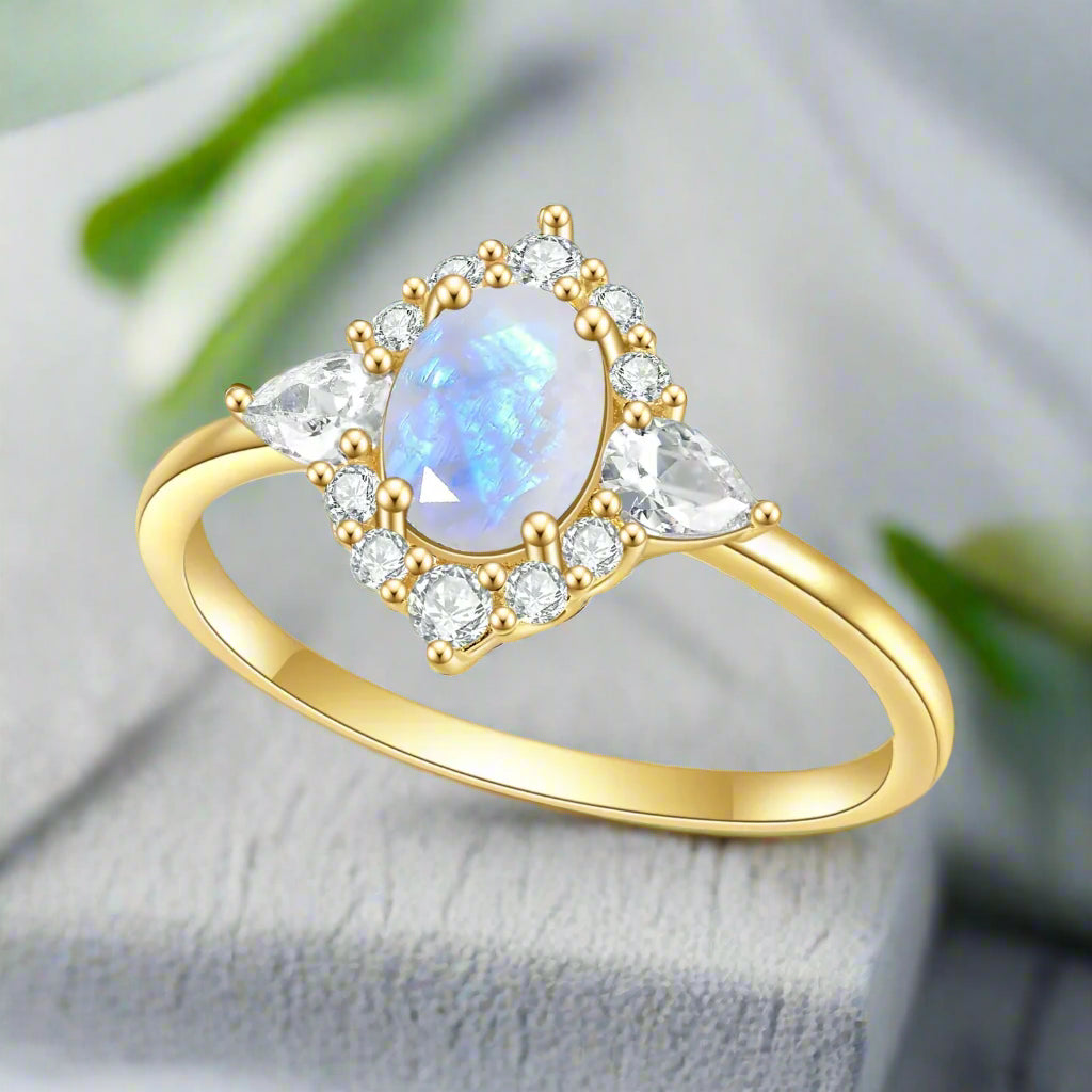 Gold ring with a teardrop-shaped gemstone and smaller diamonds on a white background