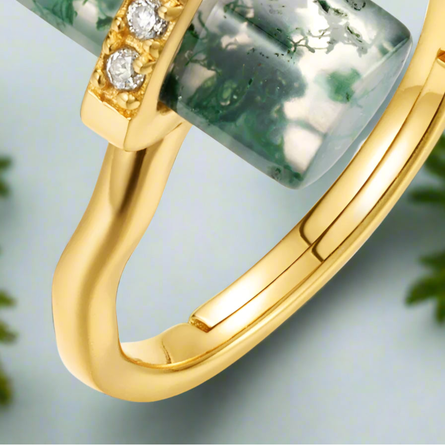 Gold ring with green gemstone and diamonds on a light gray background