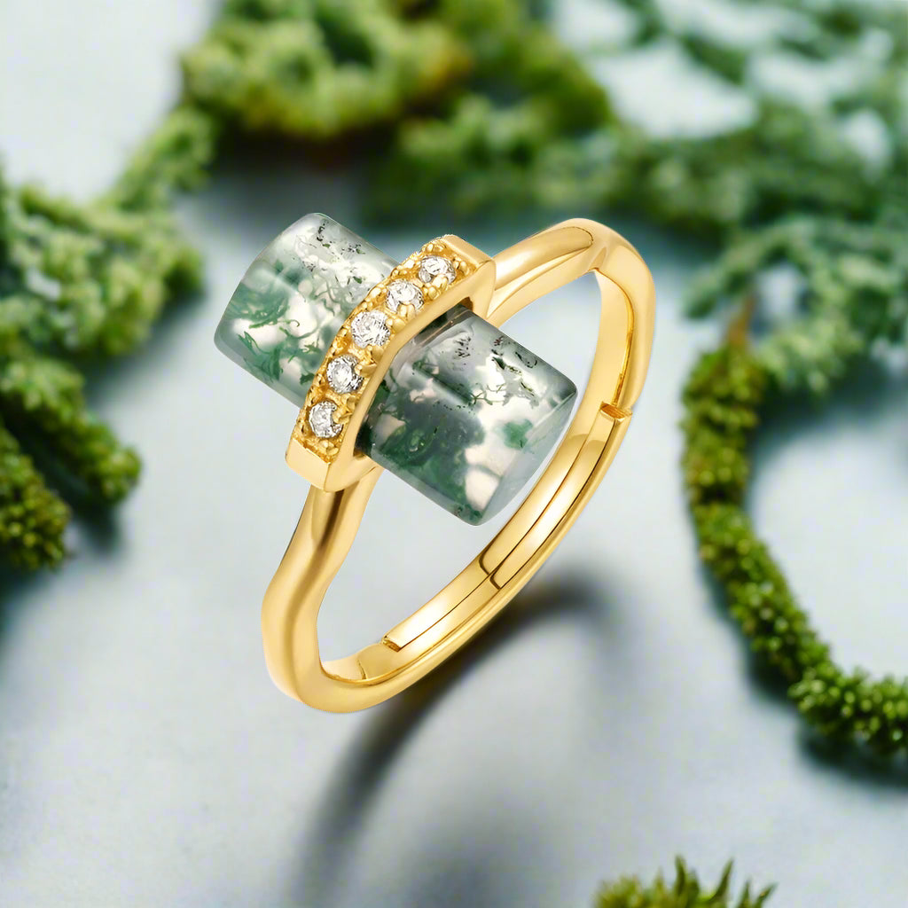 Gold ring with green gemstone and diamonds on a white background