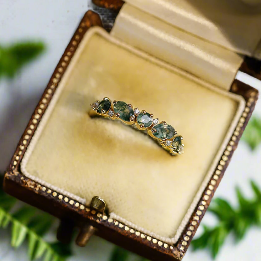 Gold ring with green gemstones in a decorative box