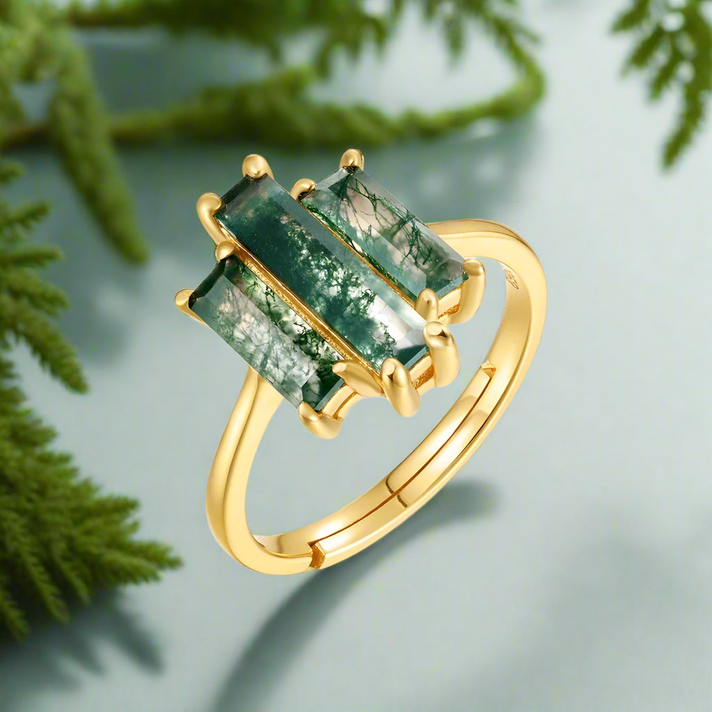 Gold ring with green gemstones on a white background