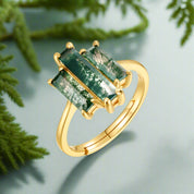 Gold ring with green gemstones on a white background