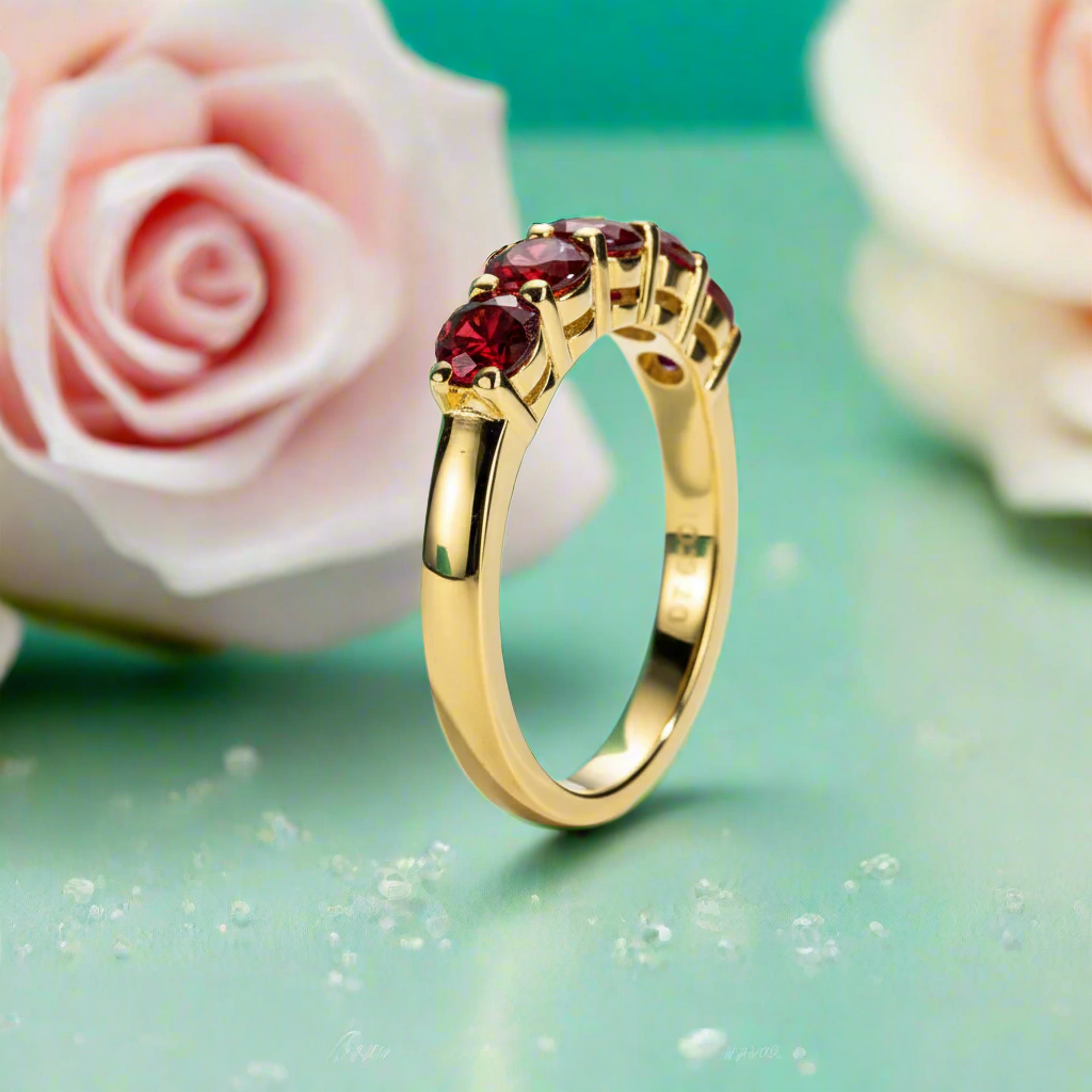 Gold ring with red gemstones on a light blue background