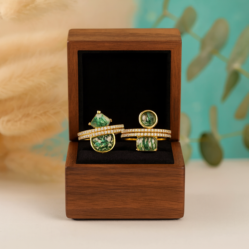 Gold rings with green gemstones in a wooden box against a natural background