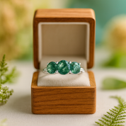 Green gemstone ring in a wooden box with a natural background